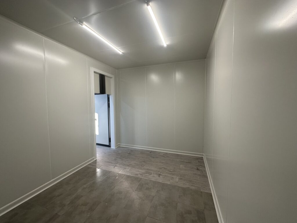 Βιομηχανικός ψυκτικός θάλαμος με είσοδο, εγκατεστημένος σε επαγγελματικό χώρο από εξειδικευμένη ψυκτική εταιρεία, με φωτισμό LED και ανθεκτικό δάπεδο.