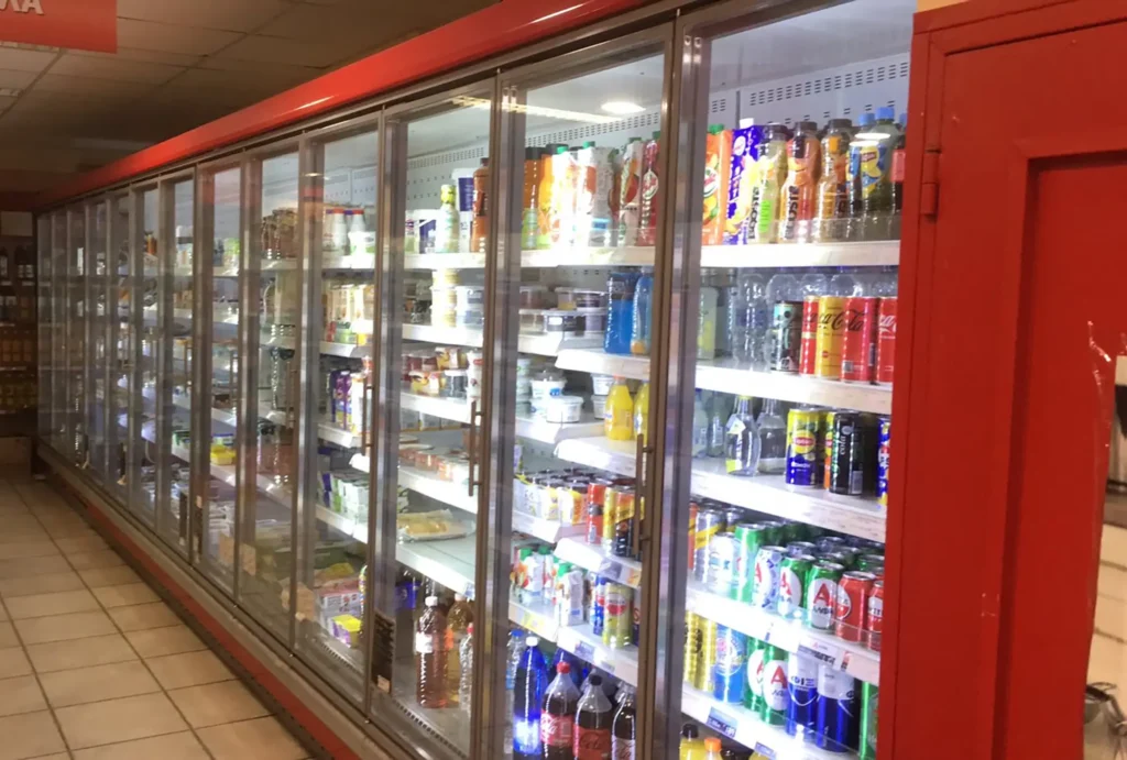 Ψυκτικές βιτρίνες με γυάλινες πόρτες σε σούπερ μάρκετ, γεμάτες με προϊόντα, εγκατεστημένες από εξειδικευμένη ψυκτική εταιρεία.