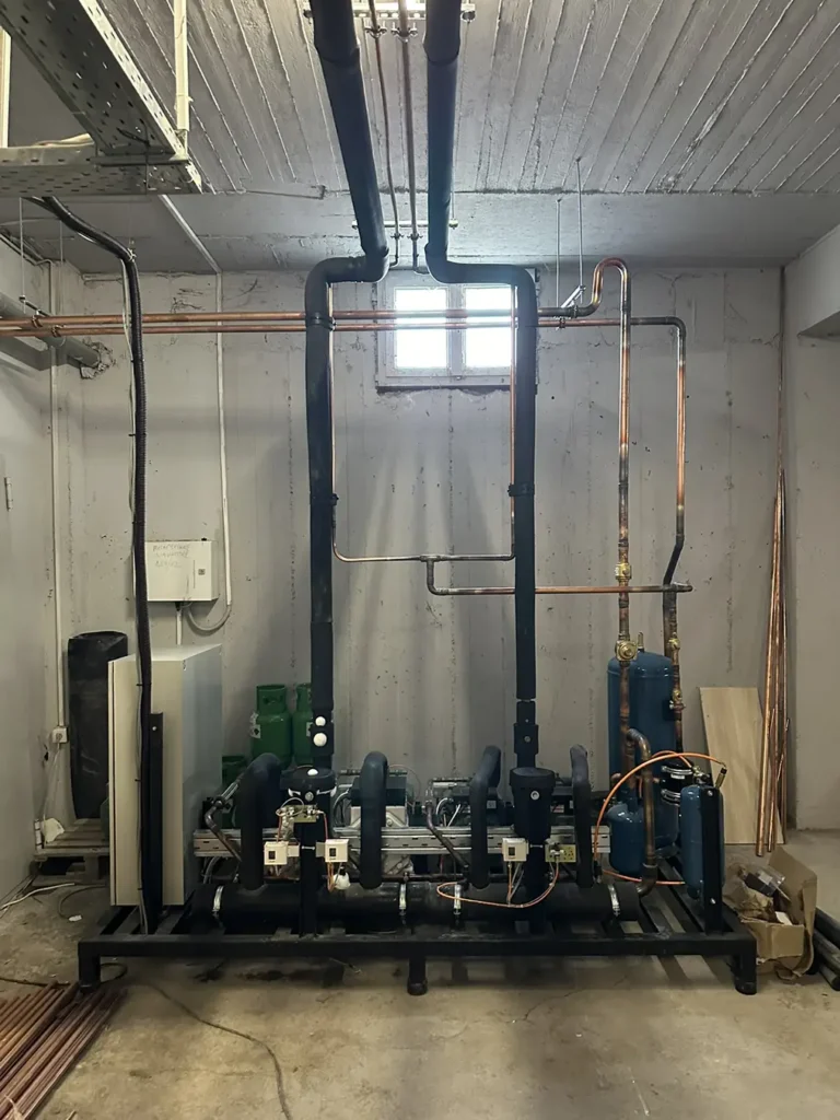 Βιομηχανικό συγκρότημα ψύξης με εκτεταμένο δίκτυο σωληνώσεων σε τεχνικό χώρο, εγκατεστημένο από εξειδικευμένη ψυκτική εταιρεία.