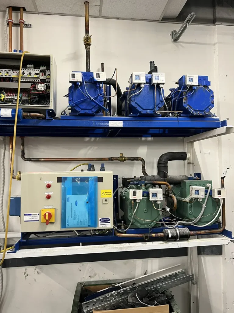 Βιομηχανικό συγκρότημα ψύξης με συμπιεστές και ηλεκτρικό πίνακα, εγκατεστημένο από εξειδικευμένη ψυκτική εταιρεία σε επαγγελματικό χώρο.